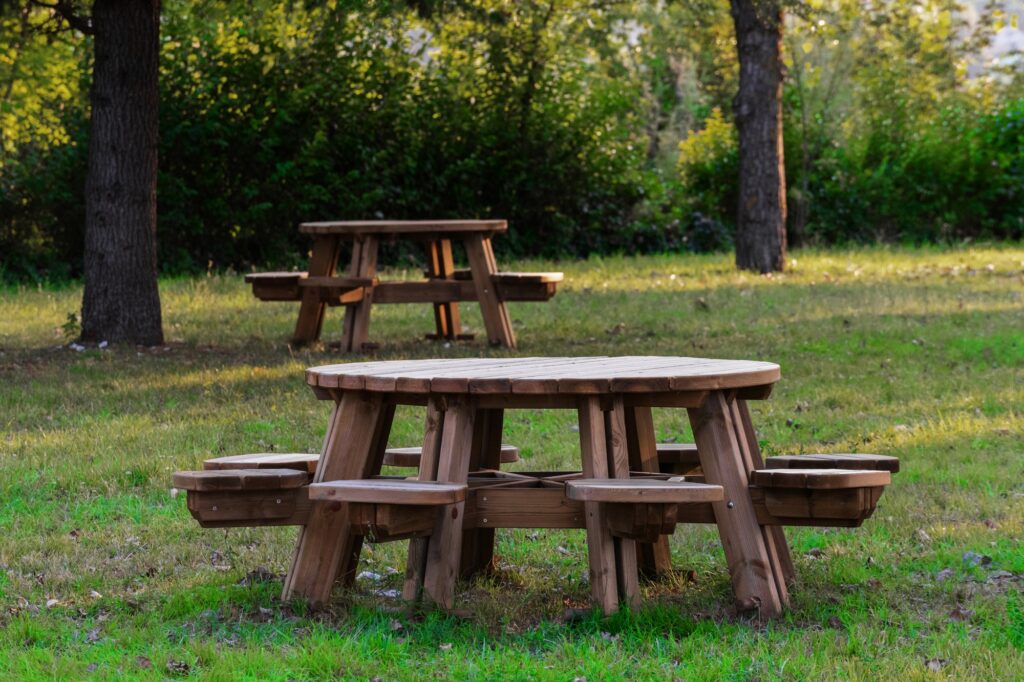 Round wooden picnic tables in a grassy park